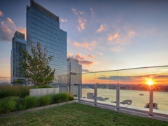 Thumbnail of Gotham West: 2717 a sunset over a body of water with a city in the background