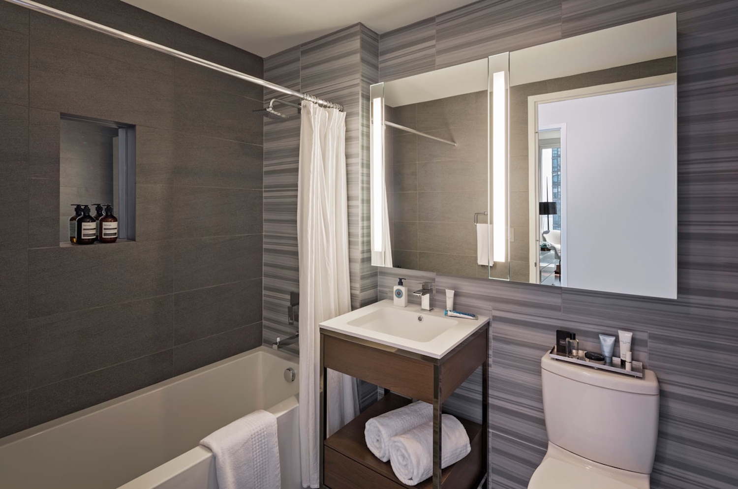 a white sink sitting under a mirror