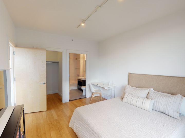 a bedroom with a bed and desk in a room