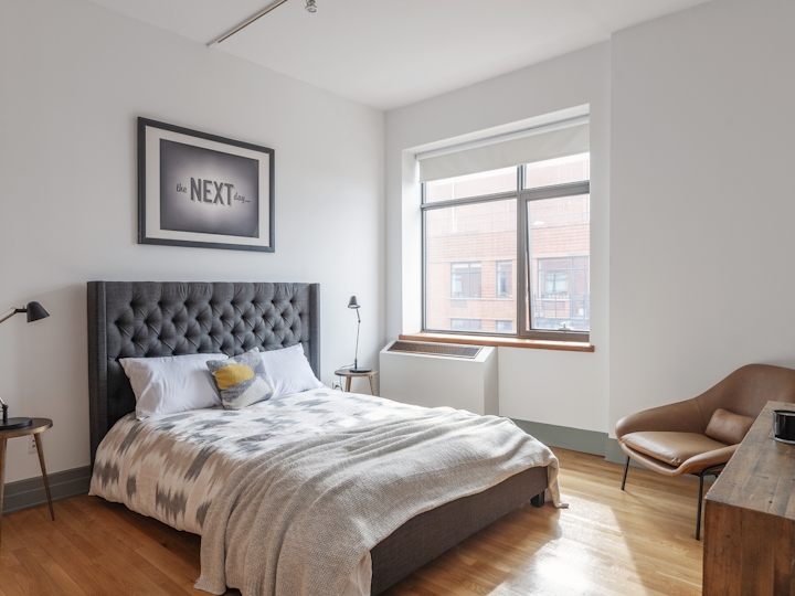 a bedroom with a bed and a chair in a room