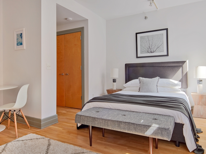 a bedroom with a bed and a chair in a room